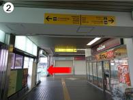 2.右側に売店が見える通路の奥に左を指している赤い矢印が記された写真